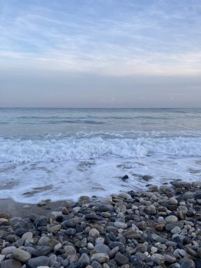 Çalkantılı deniz kum kıyısını çakıl taşlarıyla karıştırır. Yüksek kalite fotoğraf