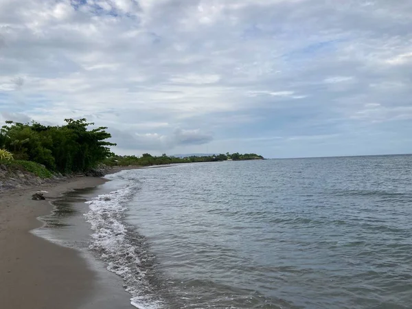 Denizin kumlu sahilinde küçük sıcak dalgalar yavaşça kıyıya vurur. Yüksek kalite fotoğraf