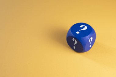 Sarı arka planda soru işareti olan mavi zarlar. Şans, risk ve seçim kavramı