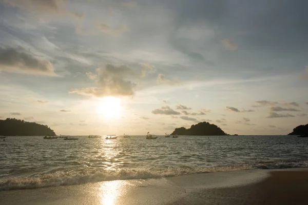 Günbatımı gökyüzü ve yüzen teknelerin silueti ve sahilde küçük bir ada Pangkor Adası, Perak, Malezya