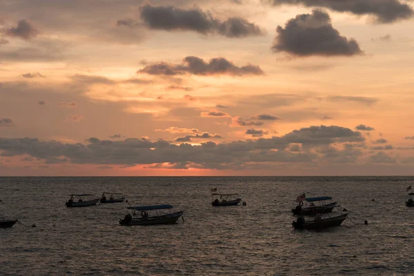 Günbatımı gökyüzü manzarası Pangkor Adası, Perak, Malezya 'da bulunan yüzen bir teknenin silüetiyle sahilde.