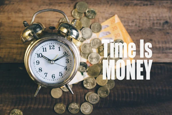 Time is money concept - Golden bell clock,money and coins on a wooden table background with 