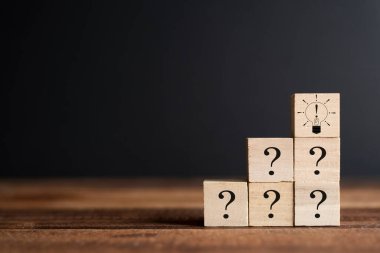 Tahta küpteki soru işareti ve ünlem işareti ampulü. SSS kavramı, sorular ve cevaplar, Beyin fırtınası ve takım oluşturma