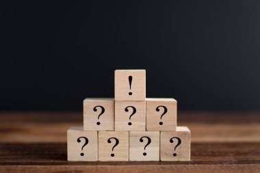 Soru işareti ve ünlem işaretiyle istiflenmiş tahta küp. Beyin fırtınası, takım çalışması, faq ve sorular kavramı
