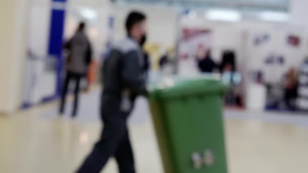 Un custode in un centro commerciale fa rotolare un contenitore per raccogliere la spazzatura — Video Stock