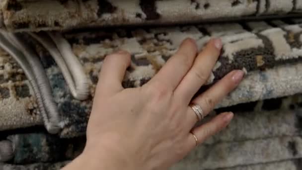 Egy nő ellenőrzi a szőnyegek minőségét a boltban.. — Stock videók