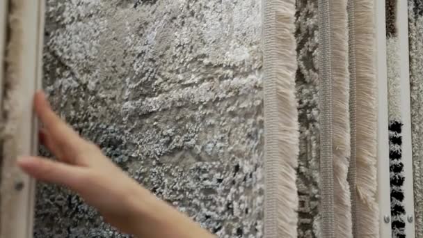 Een vrouw controleert de kwaliteit van tapijten in de winkel. — Stockvideo