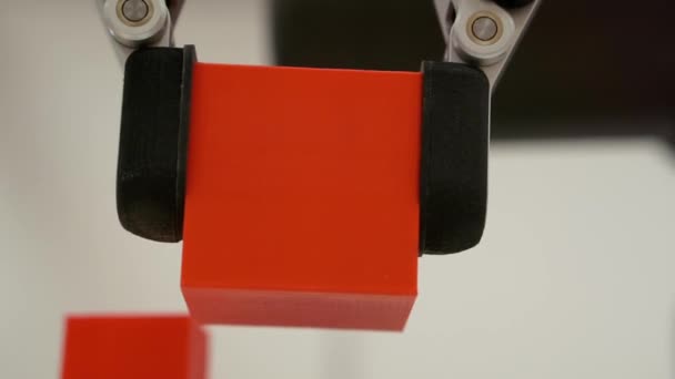 Ένας ρομποτικός βραχίονας κινεί ένα κομμάτι σε σχήμα κύβου. — Αρχείο Βίντεο