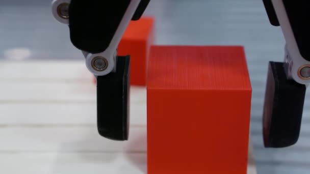 Een robotarm beweegt een kubus-vormig deel. — Stockvideo