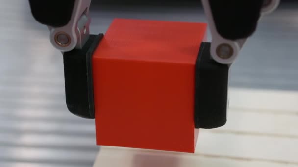 Ramię robota przesuwa część w kształcie sześcianu. — Wideo stockowe