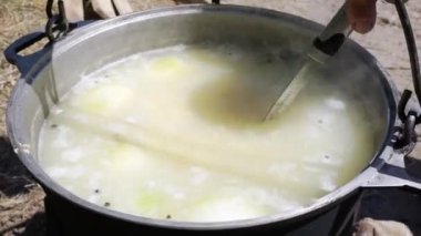 Bir turist, yürüyüş sırasında bir tencerede slotlu kaşıkla kaynamış balık çorbasını bir tencereyle karıştırır.