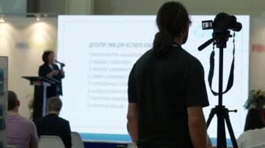 Bir kameraman konferans odasında hoparlörleri çekiyor..