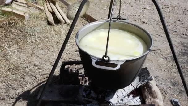 Gros plan de la soupe de poisson bouillante dans une casserole au-dessus d'un feu pendant une randonnée, un touriste interfère avec l'oreille avec une cuillère à fente — Video