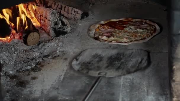 나무로 불을 때는 화덕에서 피자를 요리하는 모습. — 비디오