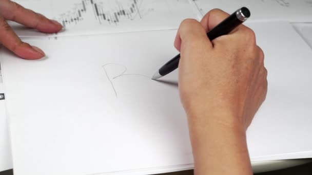 Een hand tekent de Bitcoin logo op een stuk papier met de waarschijnlijke richting van de beweging. — Stockvideo