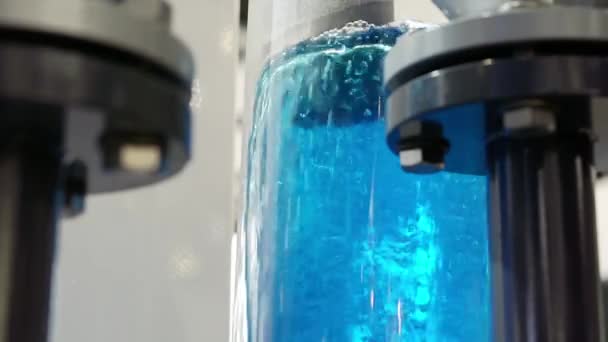 Υπάρχει ένα πίδακα μπλε νερού σε μια διαφανή φιάλη.. — Αρχείο Βίντεο