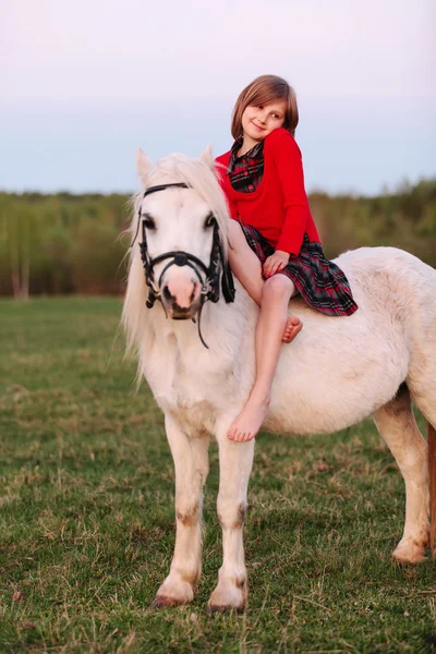 Little young lady barefoot girl sitting on a pony and shy — Stock Photo, Image