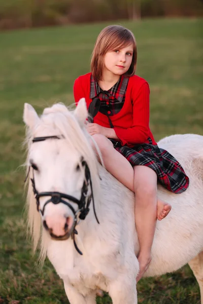 Ritratto di bambina seduta su un pony bianco — Foto Stock