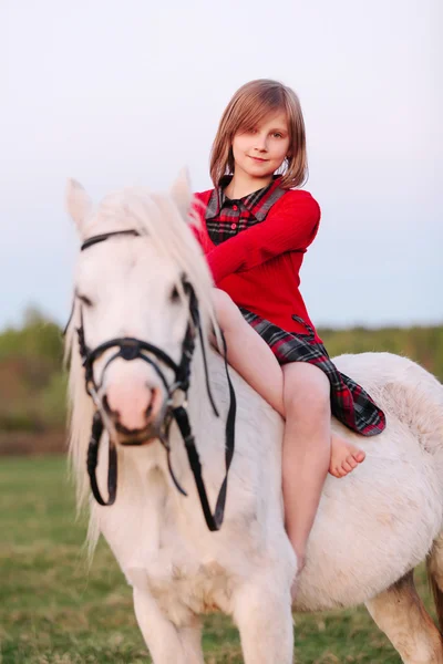 Portrait d'une petite fille assise sur un poney blanc — Photo
