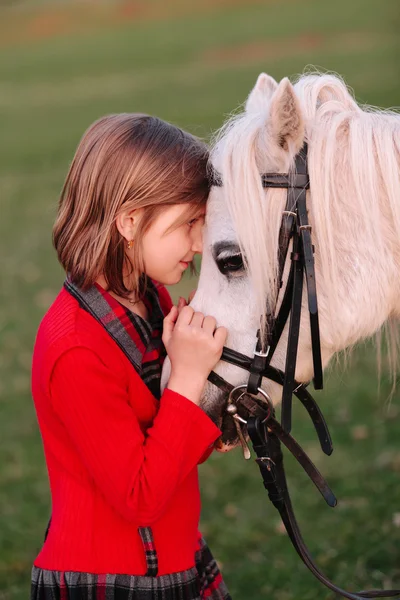 Pequena menina Pequeno cavalo branco olhando um para o outro — Fotografia de Stock