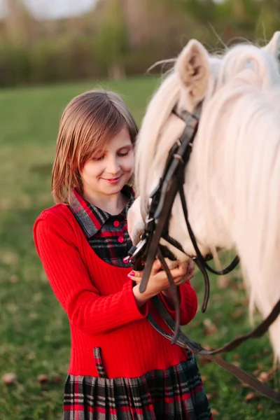 Mały model młoda dziewczyna dziecko patrzy na białym koniu — Zdjęcie stockowe