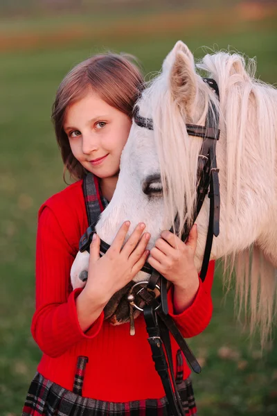 Portret van een kleine meisje model bnimaet wit paard is hoofd en kijkend naar de camera — Stockfoto