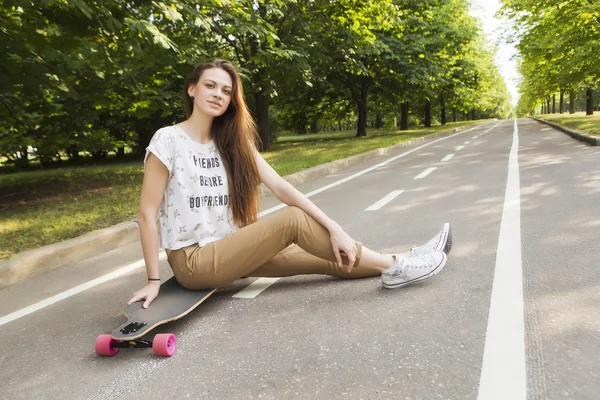ロングボードの上に座って長い髪の美しい少女のヒップなスケート ボード. — ストック写真