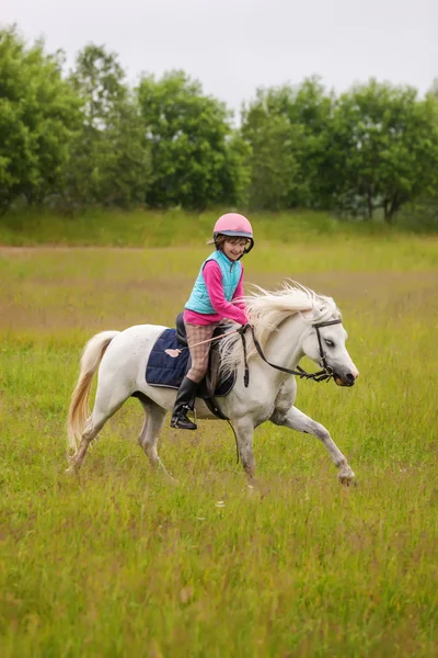 Petite fille monte un beau cheval et souriant à l'extérieur — Photo