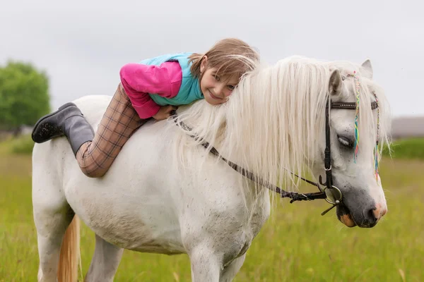 The young girl lies on the white horse back and smiling  Outdoors — Stock Photo, Image