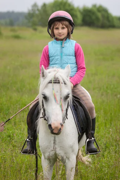 Dziewczynka w odzież do jazdy na koniu siedział ostrość na dziewczyna na zewnątrz — Zdjęcie stockowe