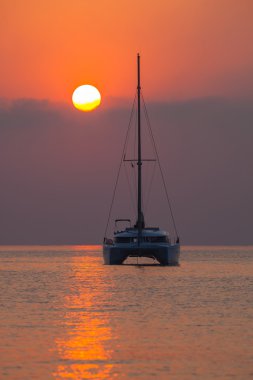Güzel bir gün batımı bir arka planda denizde yelkenli katamaran