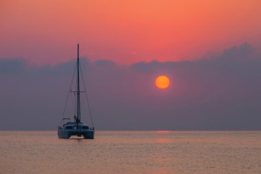 Sailing catamaran on a background of a beautiful sunset in the sea clipart