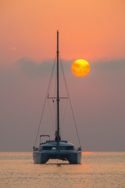 Güzel katamaran deniz gündoğumu arka plan üzerinde yelken