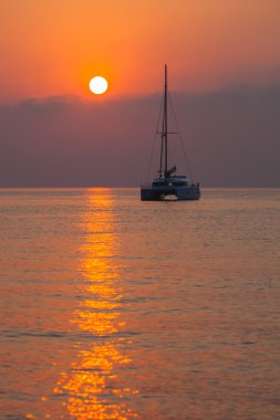 Denizin üzerinde yükselen güneşin arka plan üzerinde katamaran Yelken