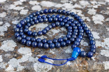 Taşın üzerinde mavi boncuklar (lapislazuli), yakın çekim ve yukarıdan görüş. Japon meditasyonu için Budist dua boncukları