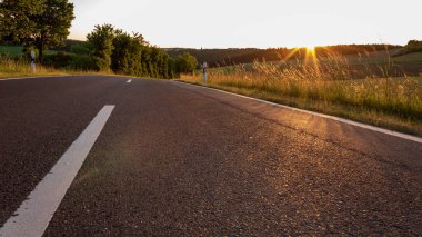 Werbach, Almanya 'da günbatımında kırsalda boş bir otoyol. Akşamları yüzey seviyesinde bölünen asfalt yolu