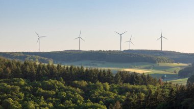 Werbach, Almanya 'nın yeşil kırsal kesiminde ufukta rüzgar türbinleri görülüyor. Alternatif yenilenebilir yeşil enerji