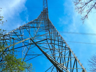 Almanya 'da mavi gökyüzüne karşı elektrik iletim direğinin alçak açılı çekimi