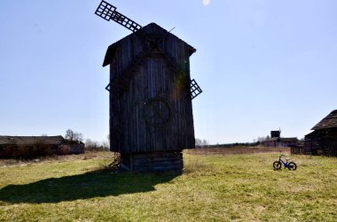 Tarladaki eski ahşap değirmeni. Değirmenin yanında çocuk bisikleti. Sahanın arka planında büyük, güzel bir değirmen. Güzel tarihi manzara.