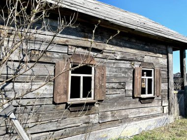 Ahşap pencereli çok eski bir ahşap ev. Ahşap bir pencerenin arka planındaki dallar. Baharda eski güzel bir ev. Köyde eski bir ev..