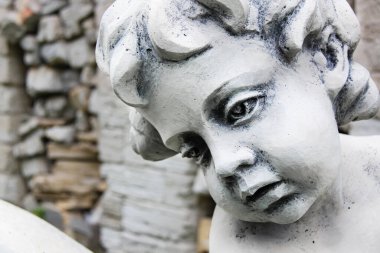 Üzgün yüzlü yaşlı taş çocuk heykelinin yakın görüntüsü