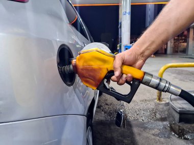 Bir el benzin istasyonundaki arabaya benzin pompalıyor. Yakıt fiyatlarında artış veya düşüş