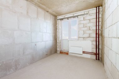 Konut binasının inşaat şantiyesiymiş. Pencereleri ve beyaz tuğlalı beton duvarı olan yeni evin iç mekanı.