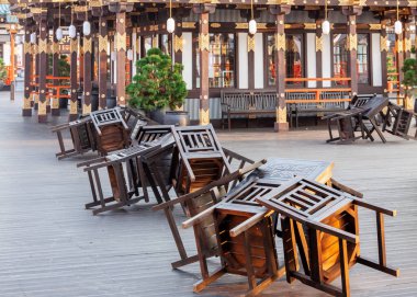 Kapalı Japon kaldırım barında ters dönmüş sandalyeler ve ahşap masalar.