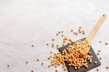 Beyaz beton arka planda tahta kaşıklı siyah nohut, düz manzaralı düz fotokopi alanı. Vejetaryen gıda ve bitki bazlı gıda sadece konsept.