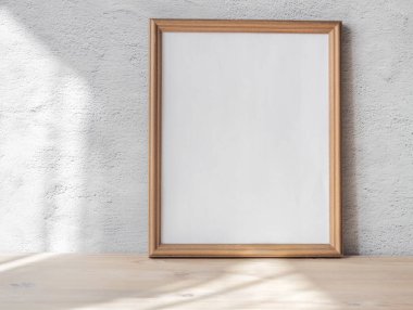 Eski ahşap bankta beyaz portre çerçeve modeli, masa beyaz gri beton arka plan. İskandinav iç mimarisi.