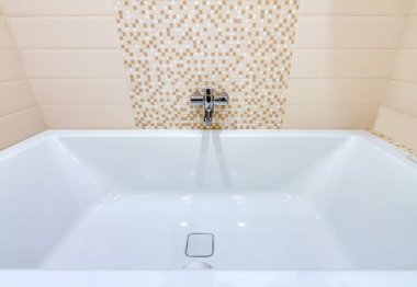 Sarı desenli seramik seramik arka planda musluğu olan beyaz modern küvet.