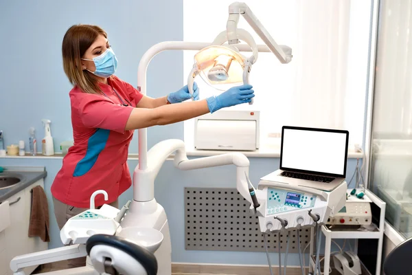 Lány fogorvos készíti a berendezések működését. Az asztalon van egy laptop-val üres üres — Stock Fotó