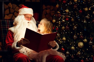 Noel Baba ve mutlu küçük bir kız sihirli bir kitap izliyor Noel Baba 'nın kucağında oturan bir çocuk