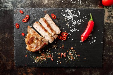 Tavada pişirilmiş domuz eti ve arka planda bulunan baharatlarla dilimlenmiş.